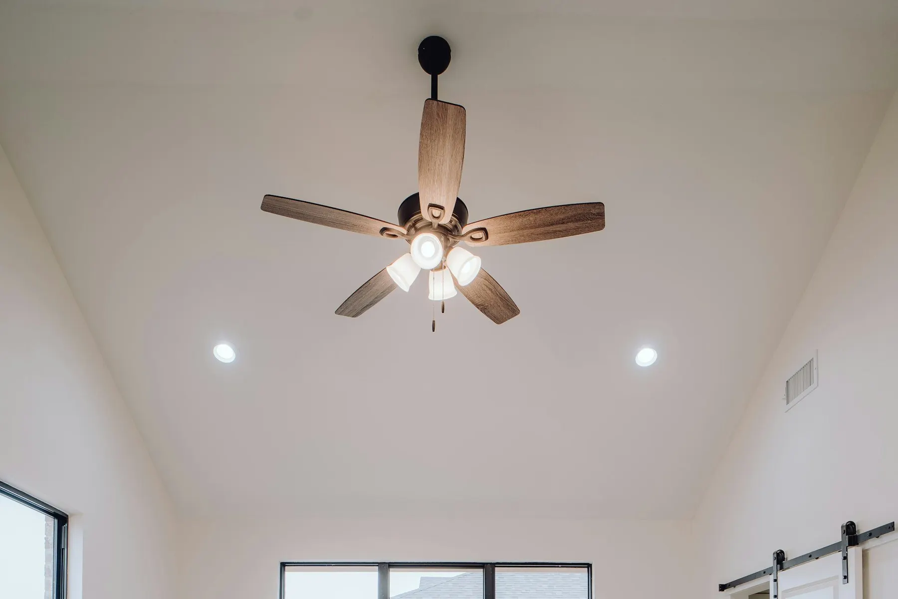 Ceiling fan with light kit and recessed lighting in a bedroom